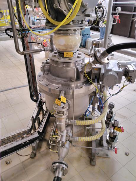 Conjunto de distribución neumática de acero inoxidable con depósito transparente, válvulas etiquetadas y tuberías flexibles amarillas para la transferencia de polvo.